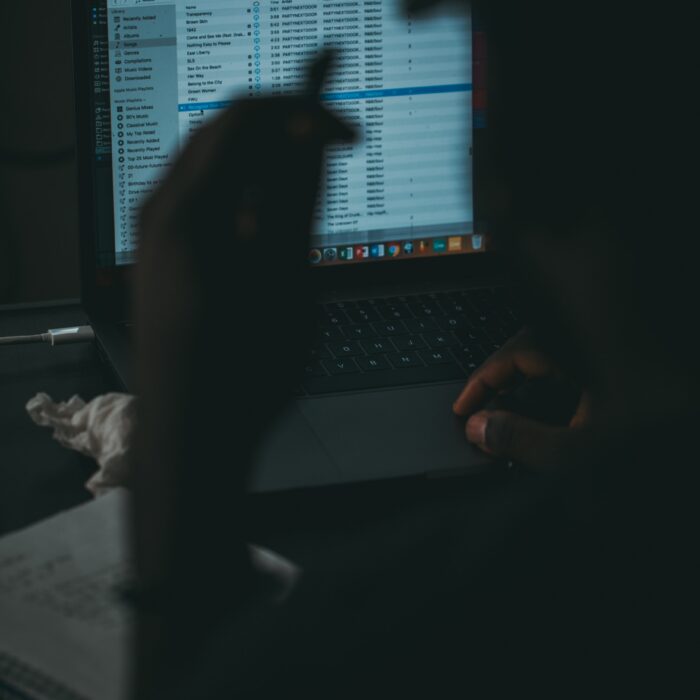 silhouette photography of man facing opened MacBook Pro with iTunes display